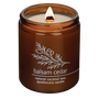 Hemlock Park Balsam Cedar apothecary candle in a brown glass jar with a lit wooden wick and botanical label design.